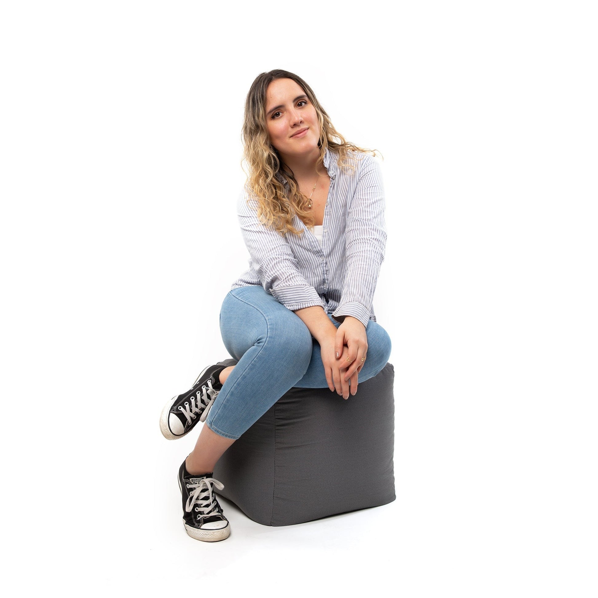 Woman sitting on a gray bean bag chair against a white background