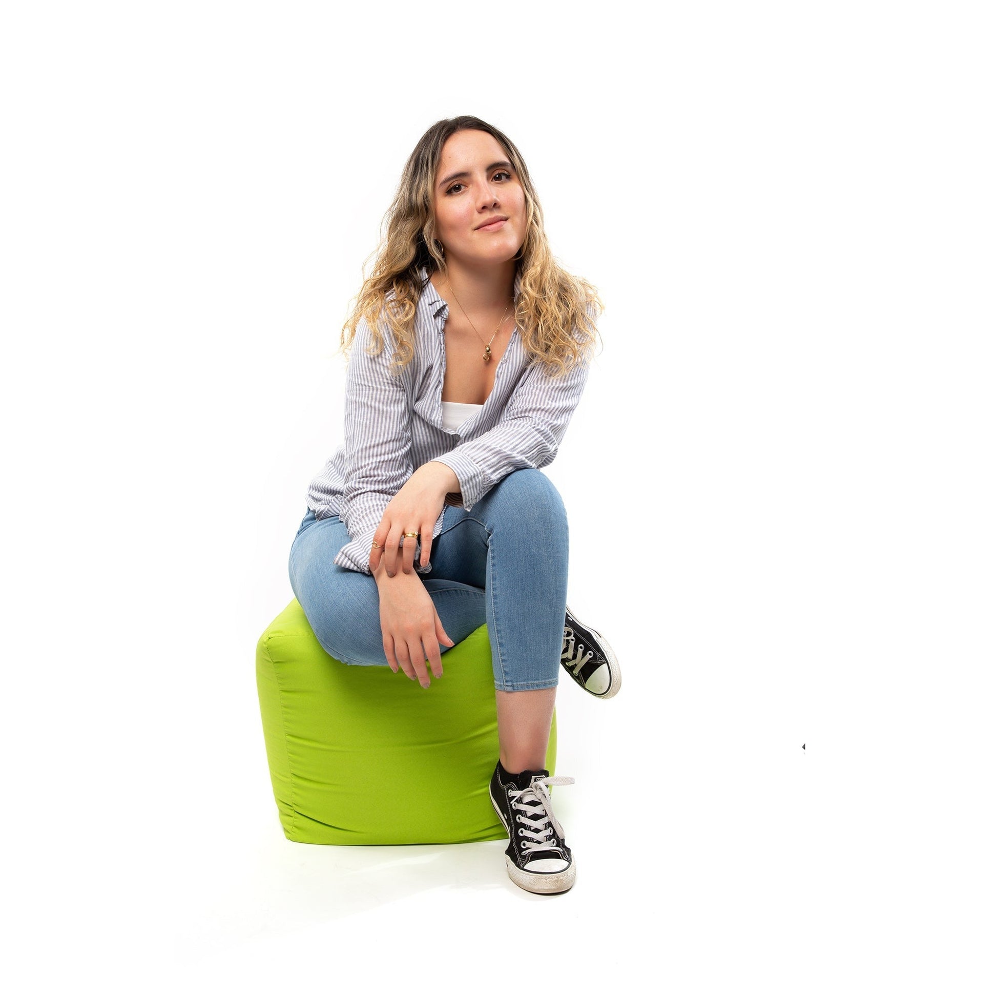 Woman sitting on a green bean bag chair against a white background