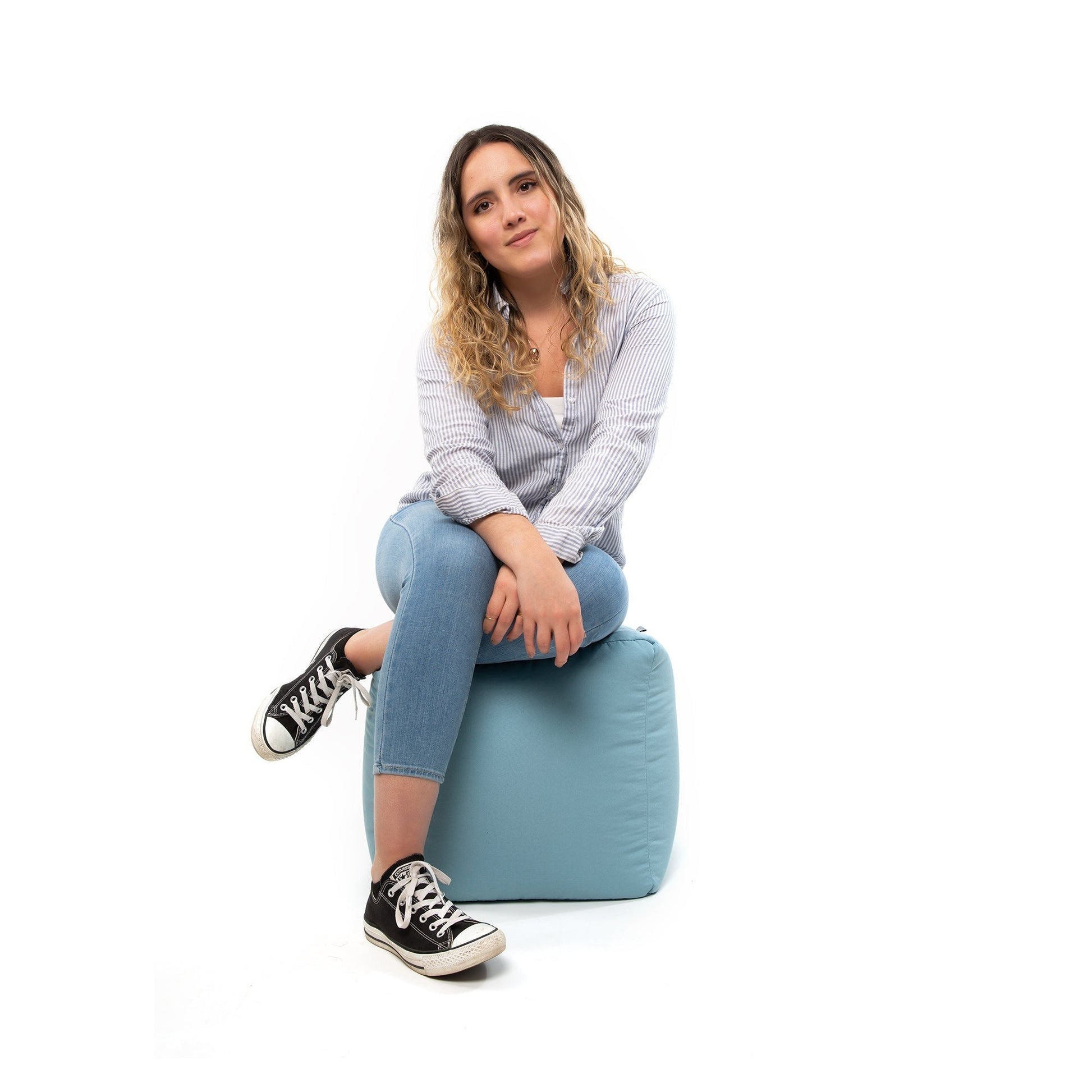 Woman sitting on a blue bean bag chair against a white background