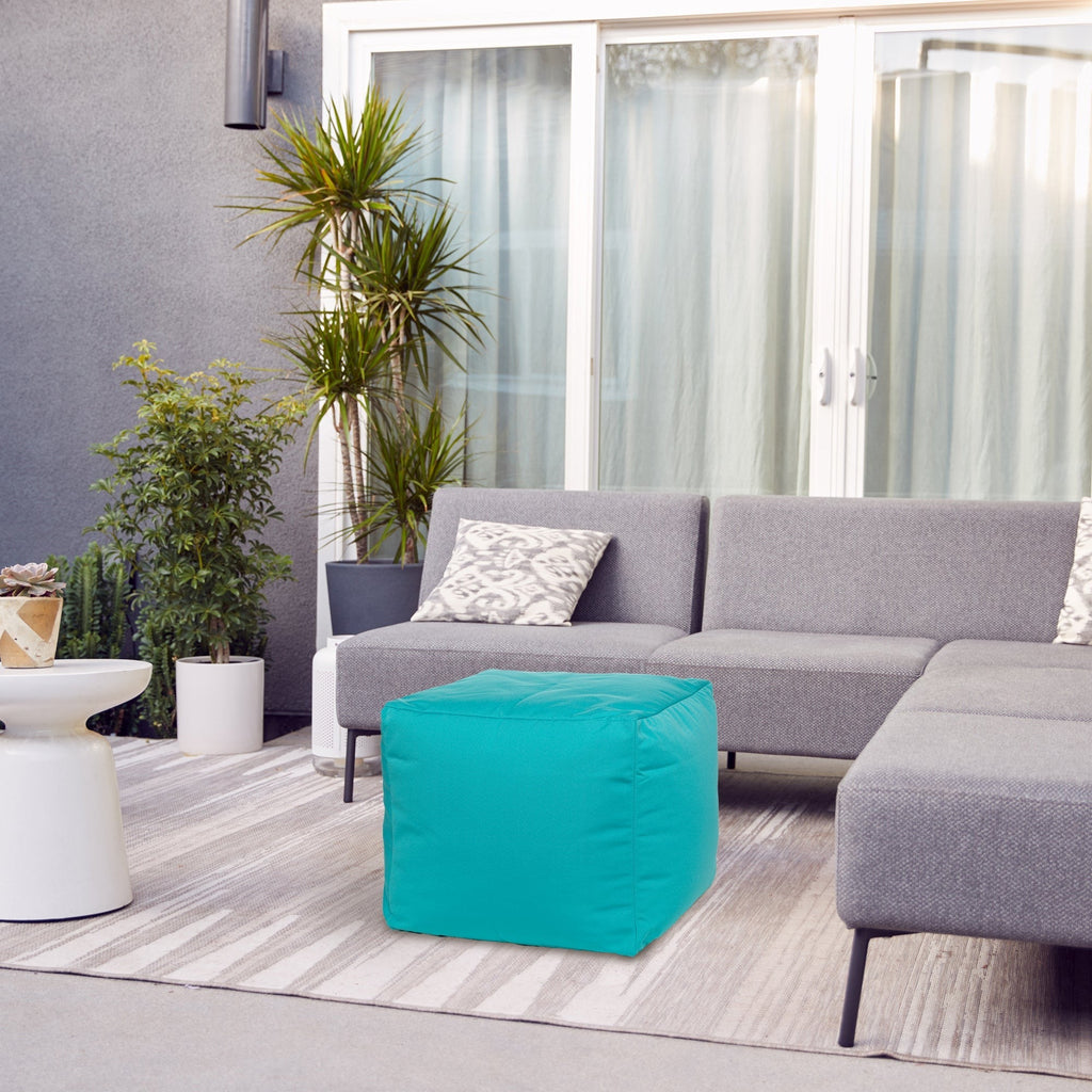 Gray sectional sofa with a teal ottoman in a modern living room setting.