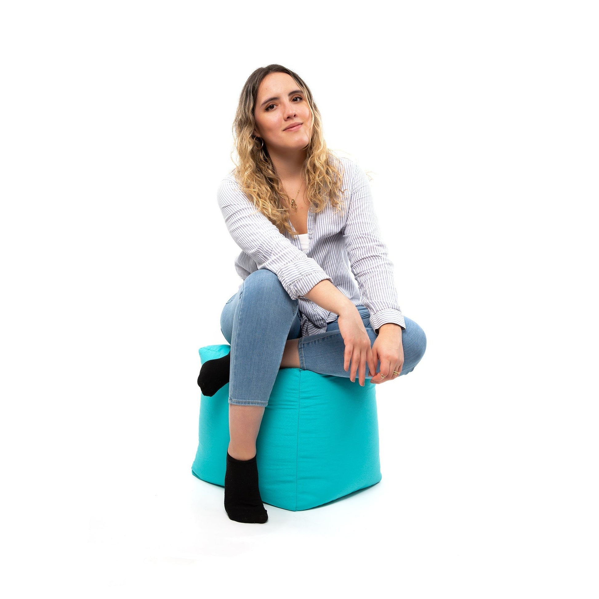 Woman sitting on a turquoise stool against a white background