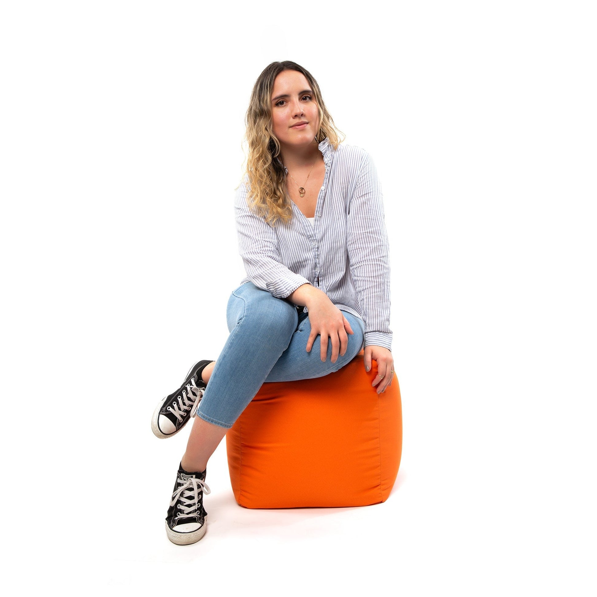 Woman sitting on an orange bean bag chair against a white background