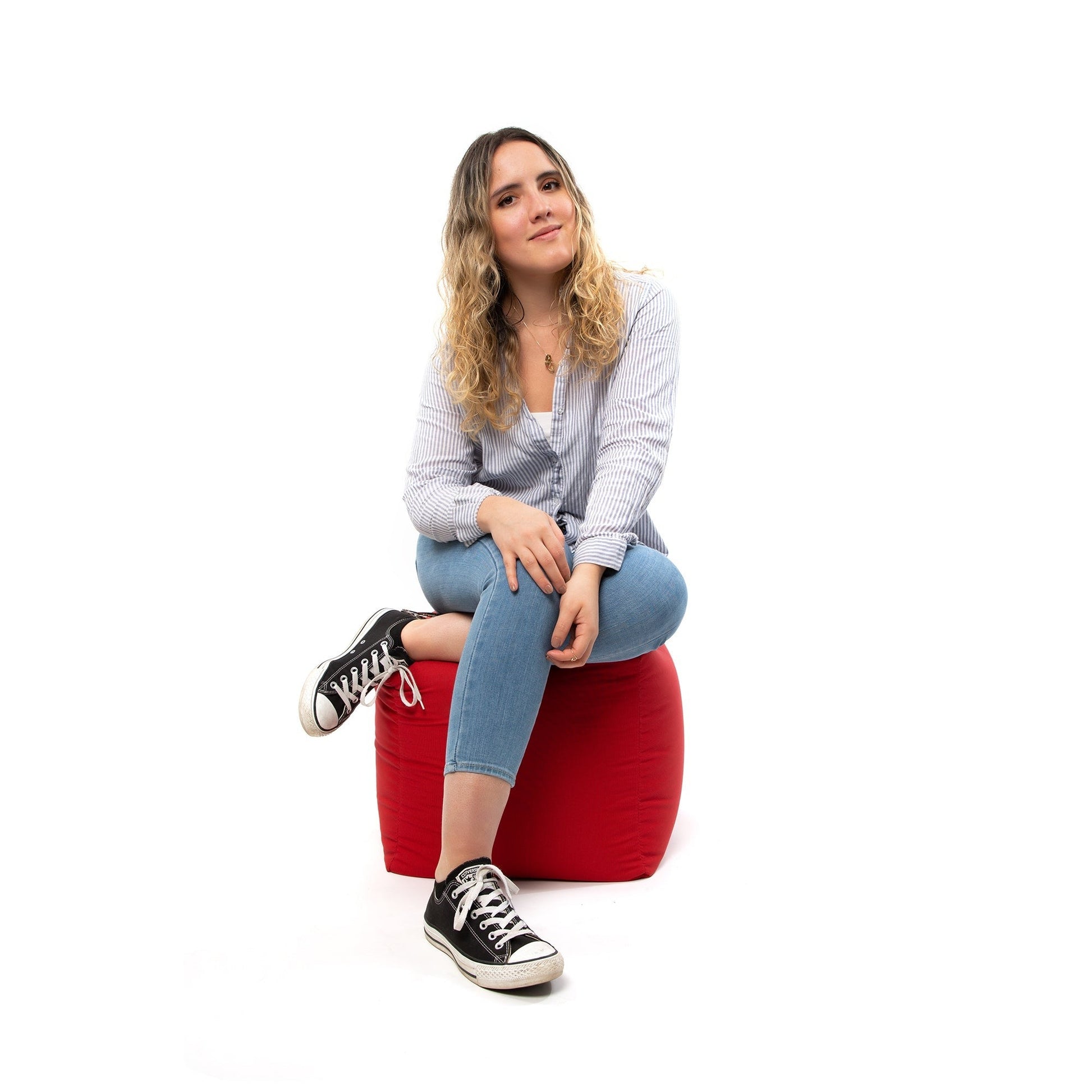Woman sitting on a red bean bag chair against a white background