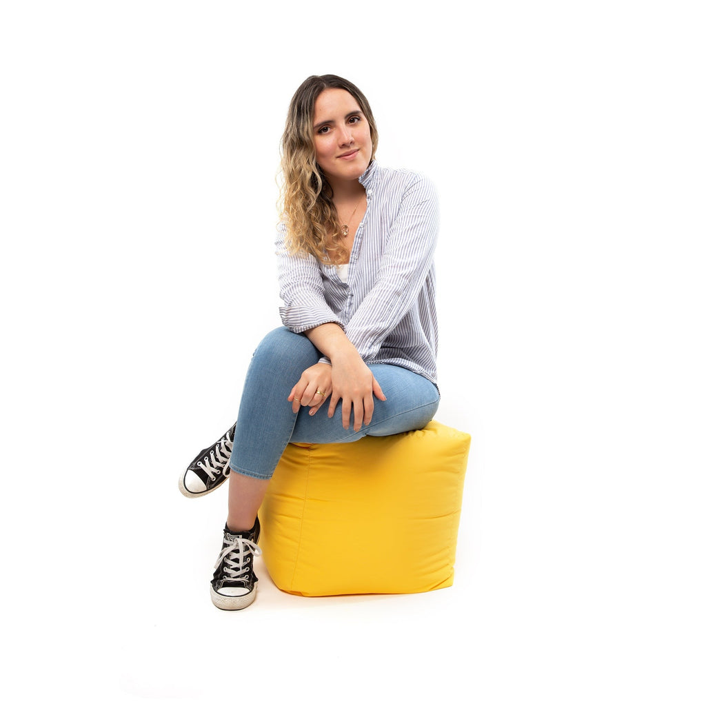 Woman sitting on a yellow bean bag chair against a white background