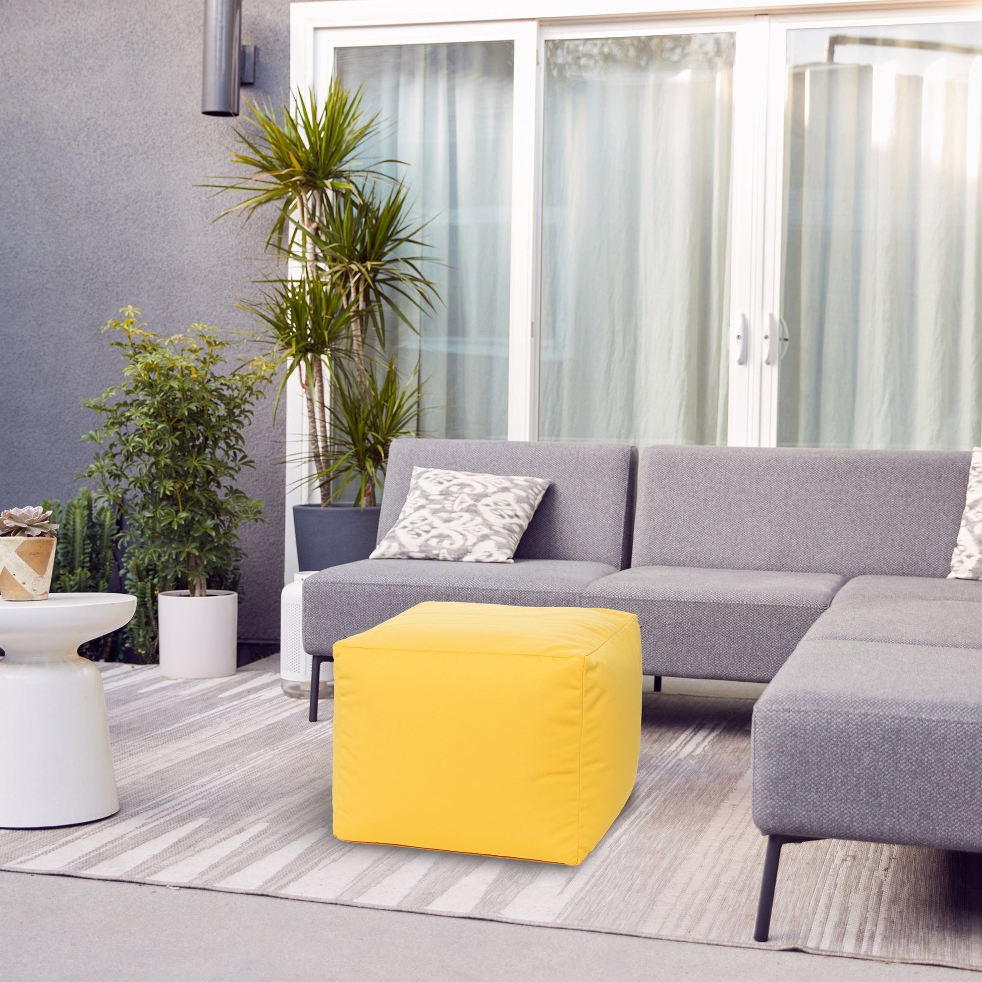 Gray sectional sofa with a yellow cube and plants in an outdoor setting