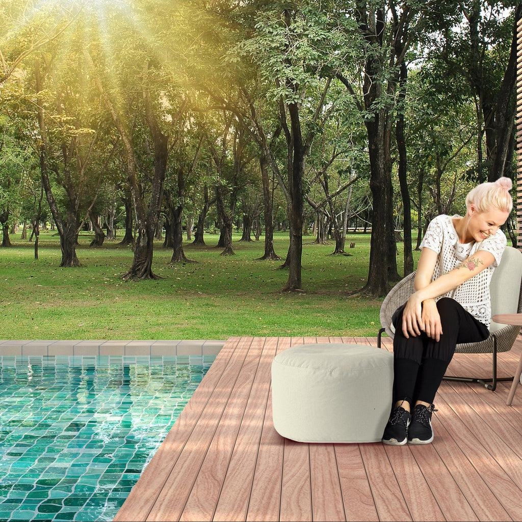 Woman sitting by a pool with trees in the background