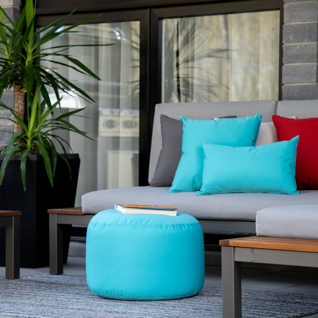 Outdoor seating area with a gray sofa, turquoise ottoman, and colorful cushions.