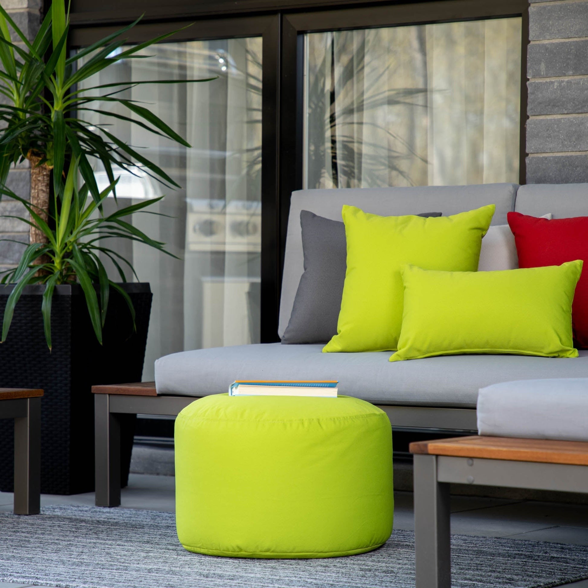 Outdoor seating area with a gray sofa and colorful cushions, including a green ottoman.