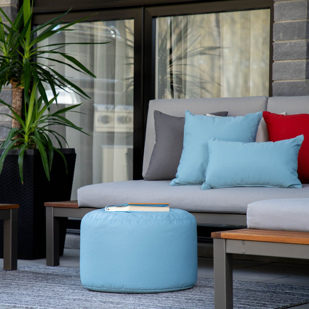 Outdoor seating area with a gray sofa, blue ottoman, and colorful cushions.