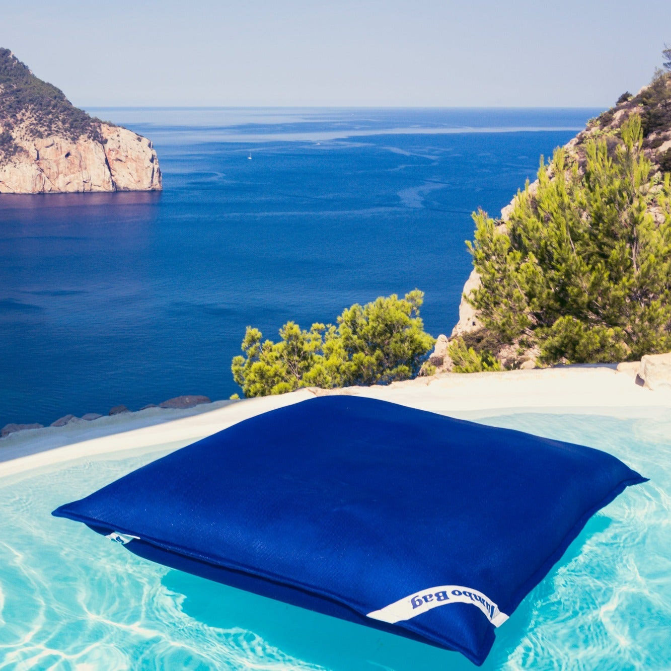 Blue inflatable pool float in a pool with a scenic ocean view.
