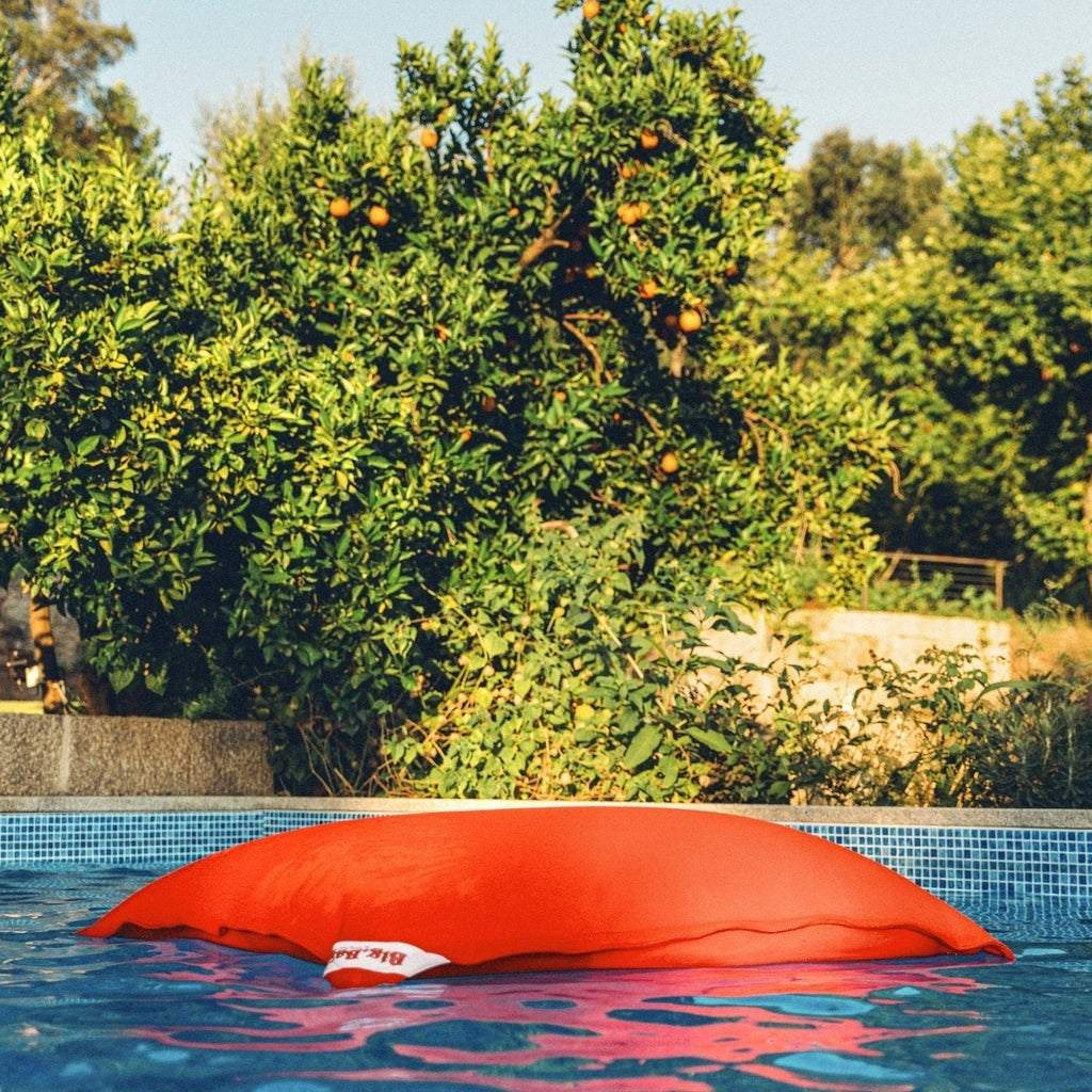 Red pool floatie floating in a pool with trees in the background