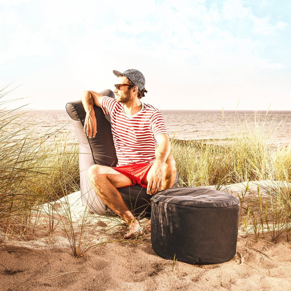 Man sitting on a chair in sand dunes with a scenic beach background