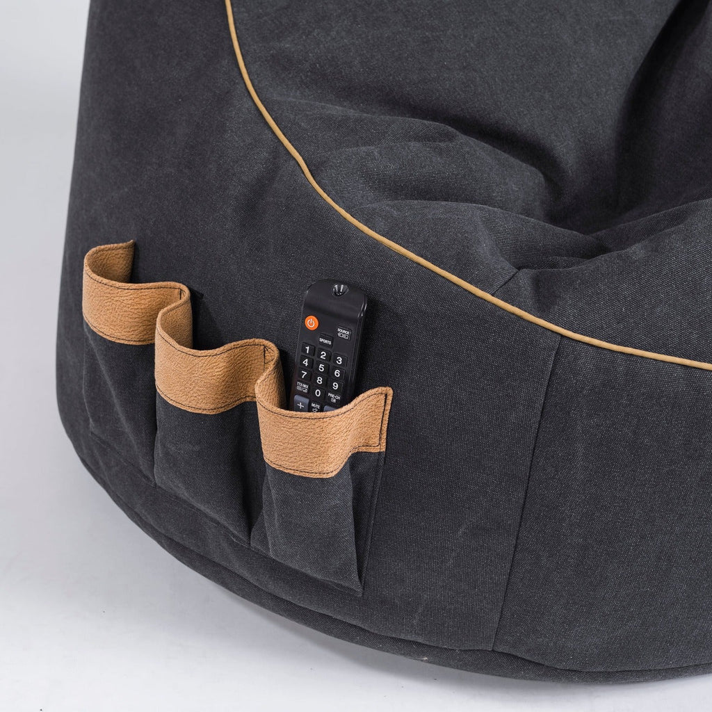 Dark gray bean bag with brown pockets and a remote control on a light gray background
