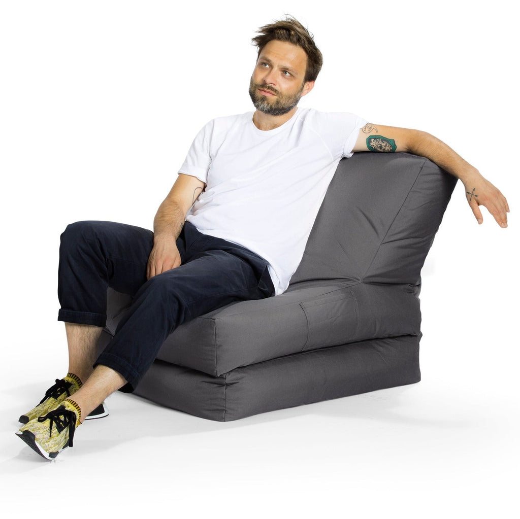 Man sitting on a gray bean bag chair against a white background
