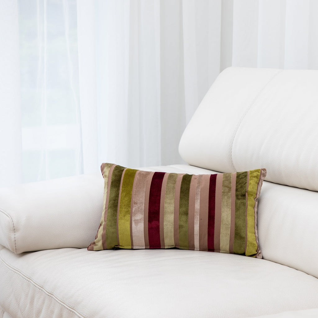 Striped pillow on a white couch with a white curtain background